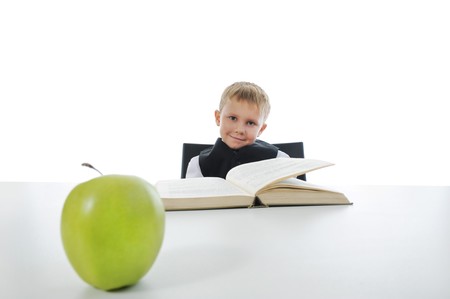 boy at the desk reading a book. Isolated on white background