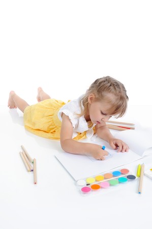 Girl draws on the album. Isolated on white backgroundの写真素材