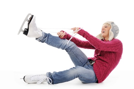 Beautiful girl in winter clothes puts on skates. Isolated on white backgroundの写真素材