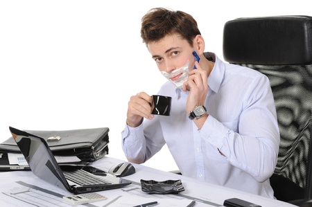 Businessman shaves in the workplace. Isolated on white backgroundの写真素材