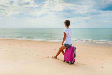 Young woman with a suitcase on the beachの写真素材