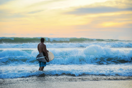Young surfer with board on the beachの写真素材