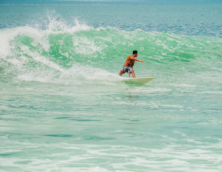 Athletic surfer with board on a wave in the ocean