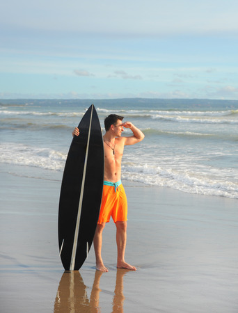 Young surfer with board on the beachの写真素材