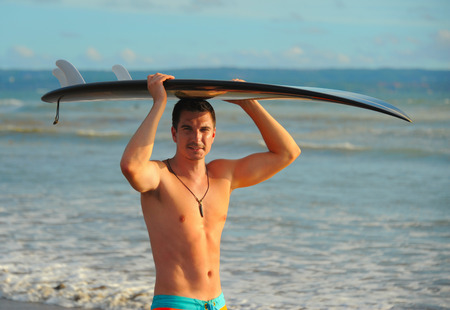 Young surfer with board on the beachの写真素材
