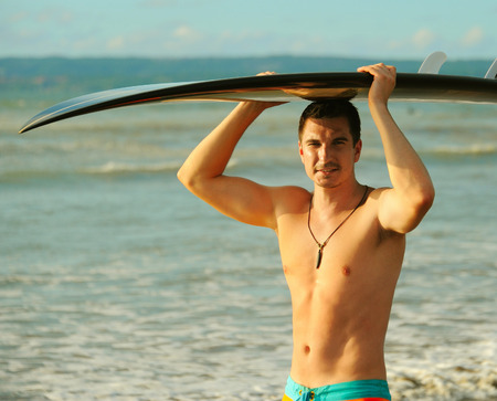 Young surfer with board on the beachの写真素材