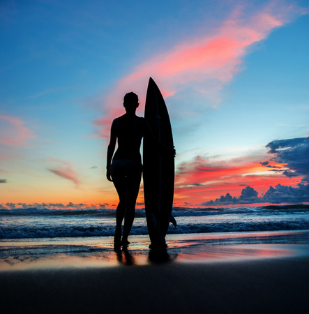 Beautiful young woman surfer with board on the beachの写真素材