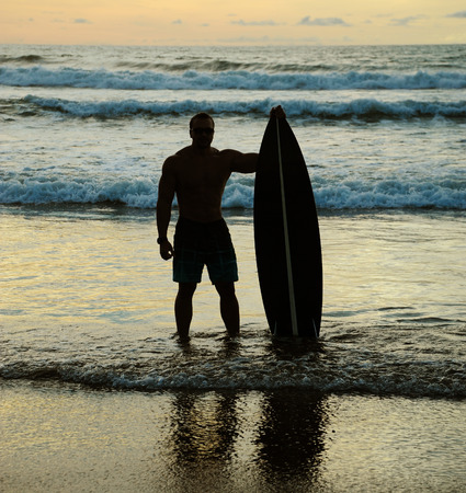 Young surfer with board on the beachの写真素材