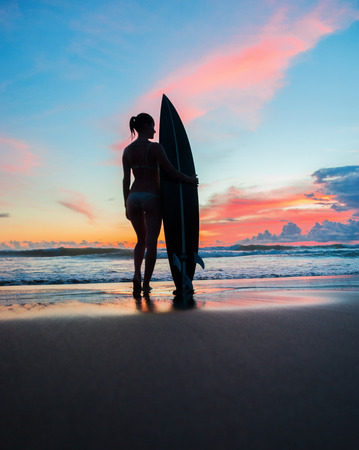 Beautiful young woman surfer with board on the beachの写真素材