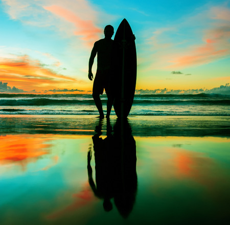 Young surfer with board on the beachの写真素材