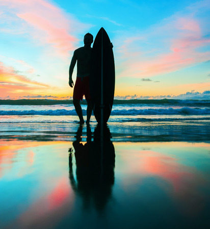 Young surfer with board on the beachの写真素材