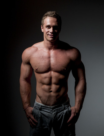 bodybuilder posing. Handsome power athletic guy male. Fitness muscular body on black background.の写真素材
