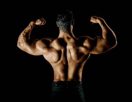bodybuilder posing. Handsome power athletic guy male. Fitness muscular body on black background.の写真素材