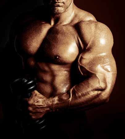 bodybuilder posing. Handsome power athletic guy male. Fitness muscular body on black background.の写真素材