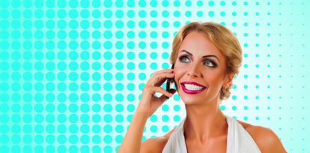 Portrait happy young woman talking on mobile phone on color backgroundの写真素材