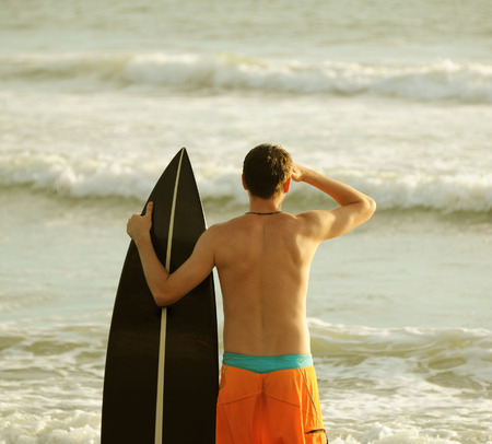 Young surfer with board on the beachの写真素材