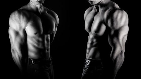 bodybuilder posing. Handsome power athletic guy male. Fitness muscular body on black background. Black and white photoの写真素材
