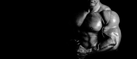 bodybuilder posing. Handsome power athletic guy male. Fitness muscular body on black background. Black and white photoの写真素材