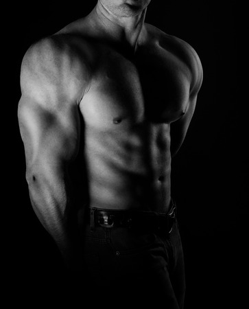 bodybuilder posing. Handsome power athletic guy male. Fitness muscular body on black background. Black and white photoの写真素材
