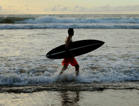 Young surfer with board on the beachの写真素材