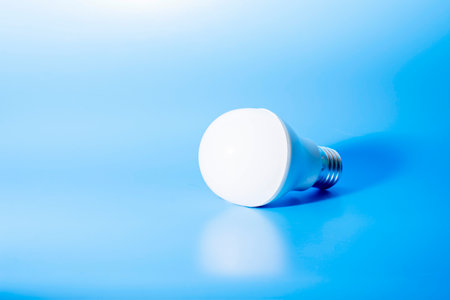 a glowing led light bulb casts a shadow on a blue background. conceptual photography. High quality photoの写真素材