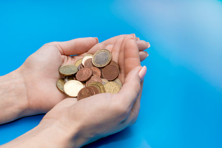 coins in the palms of a woman on a blue background. euro cents. High quality photoの写真素材