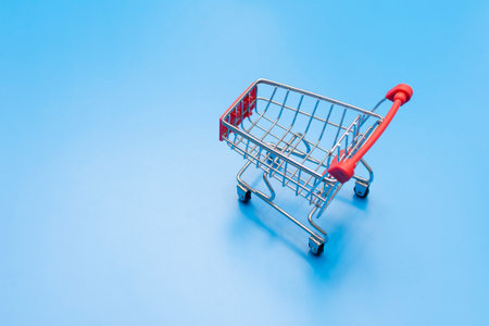 empty metal shopping trolley on blue background. High quality photo
