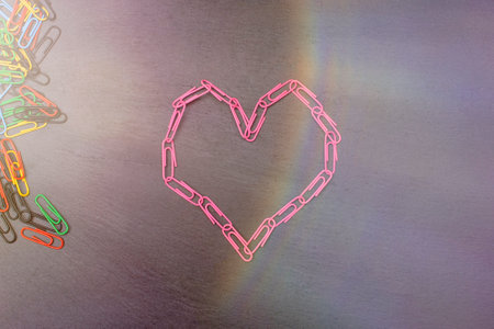 heart symbol made of pink paper clips on a dark background. High quality photo