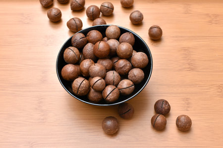 macadamia nuts in a black bowl on a wooden background. High quality photoの写真素材