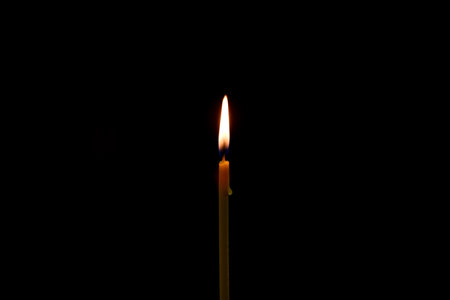 a candle burns in the dark on a black background. dripping drop of wax. High quality photoの写真素材