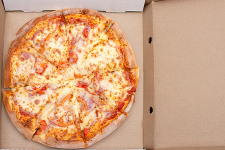 pizza with meat, cheese and vegetables in a cardboard box for delivery. High quality photoの写真素材