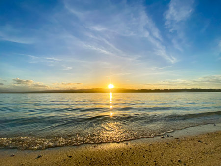 Beautiful sunrise over the sea with waves and sand, blue sky. High quality photoの写真素材