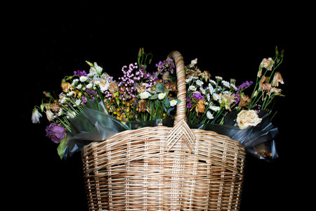 wicker basket with withered flowers in it on a dark background. High quality photoの写真素材