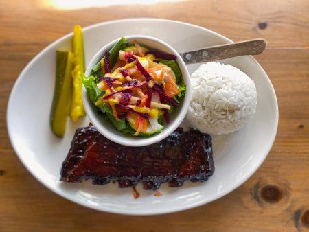 caramelized fried BBQ beef ribs with vegetable salad, rice and pickled cucumbersの写真素材