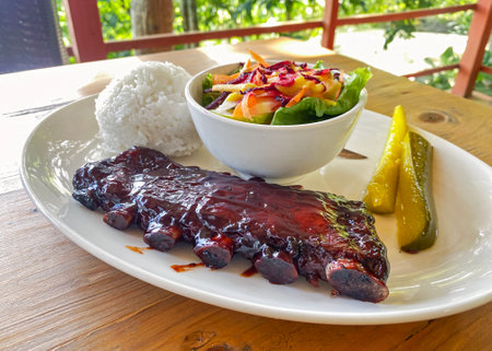 caramelized fried BBQ beef ribs with vegetable salad, rice and pickled cucumbersの写真素材