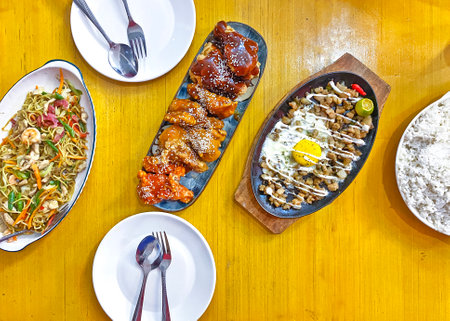 Filipino cuisine served on the table, sizzling sisig, seafood pancit, rice and chicken wings in sweet and sour sauceの写真素材