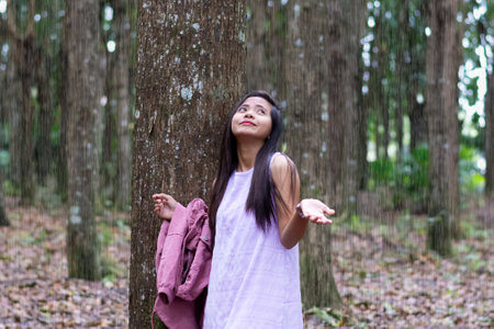beautiful young asian woman hiding from tropical rain under a treeの写真素材
