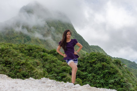 Portrait of a beautiful young Filipina woman against the backdrop of tropical mountains covered with clouds.の写真素材