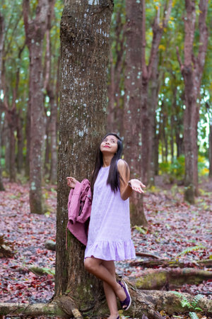 beautiful young woman hiding from tropical rain under a tree.の写真素材