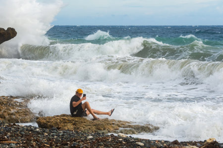 a man takes a selfie near the waves of the ocean.の写真素材