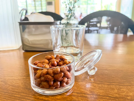 salted peanuts in a glass vase with an open lid on a table in a cafeの写真素材