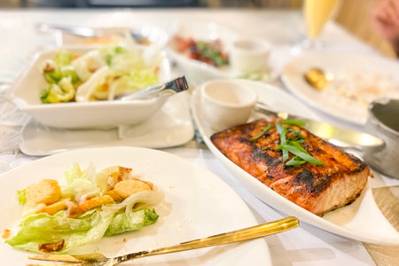 tuna steak and caesar salad on a table in a restaurantの写真素材