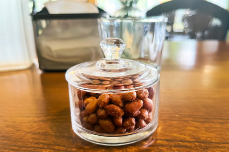 salted peanuts in a glass vase with a lid on a table in a cafeの写真素材