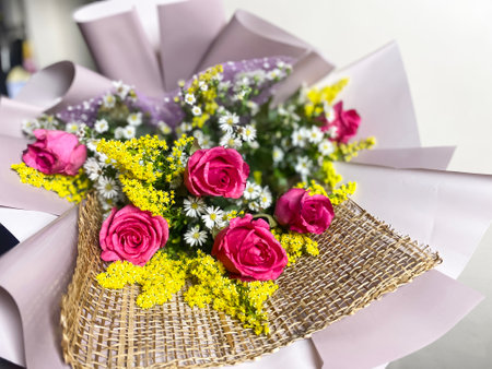delicate bouquet with roses in purple paper complemented by small yellow flowersの写真素材