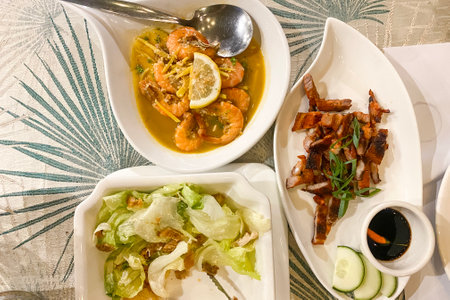 crispy fried pork belly, butter shrimp and caesar salad served on platesの写真素材