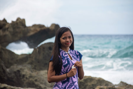 Woman posing on rocky shore with waves behind her