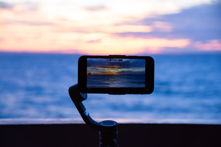 Smartphone filming a sunset over the oceanの写真素材