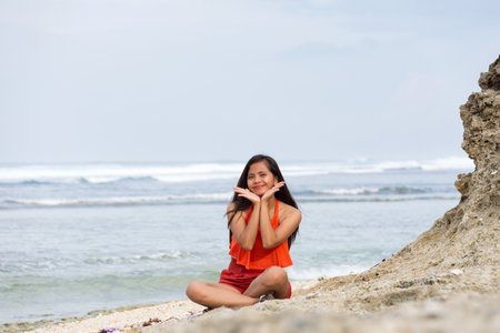 Happy woman sitting on the beach with waves in the backgroundの写真素材