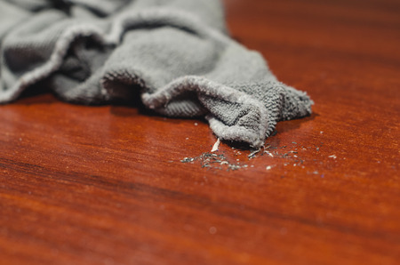 Grey wet rag on the dirty wooden desk. Cleaning the house or doing household chores concept.の写真素材