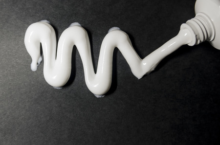 White toothbrush with white toothpaste on the black background. Squeeizing the  tooth tube and cleaning teeth concept. Morning routine.の写真素材